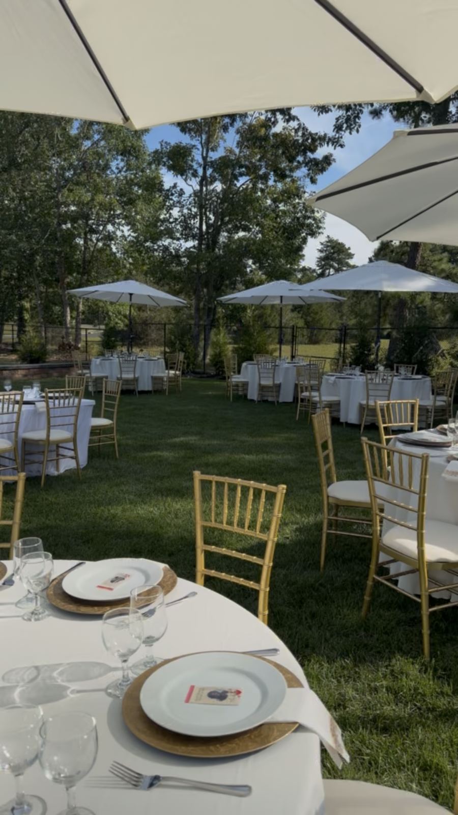 Gold chiavari chairs with white cushions around tables set with gold chargers