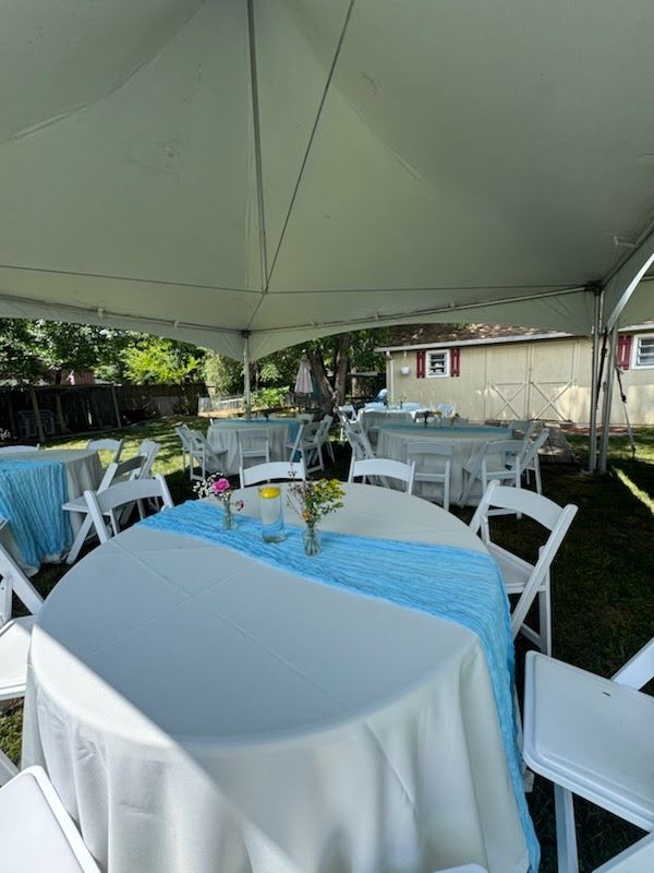 Under a high-peak tent: round tables with white linens and light blue runners